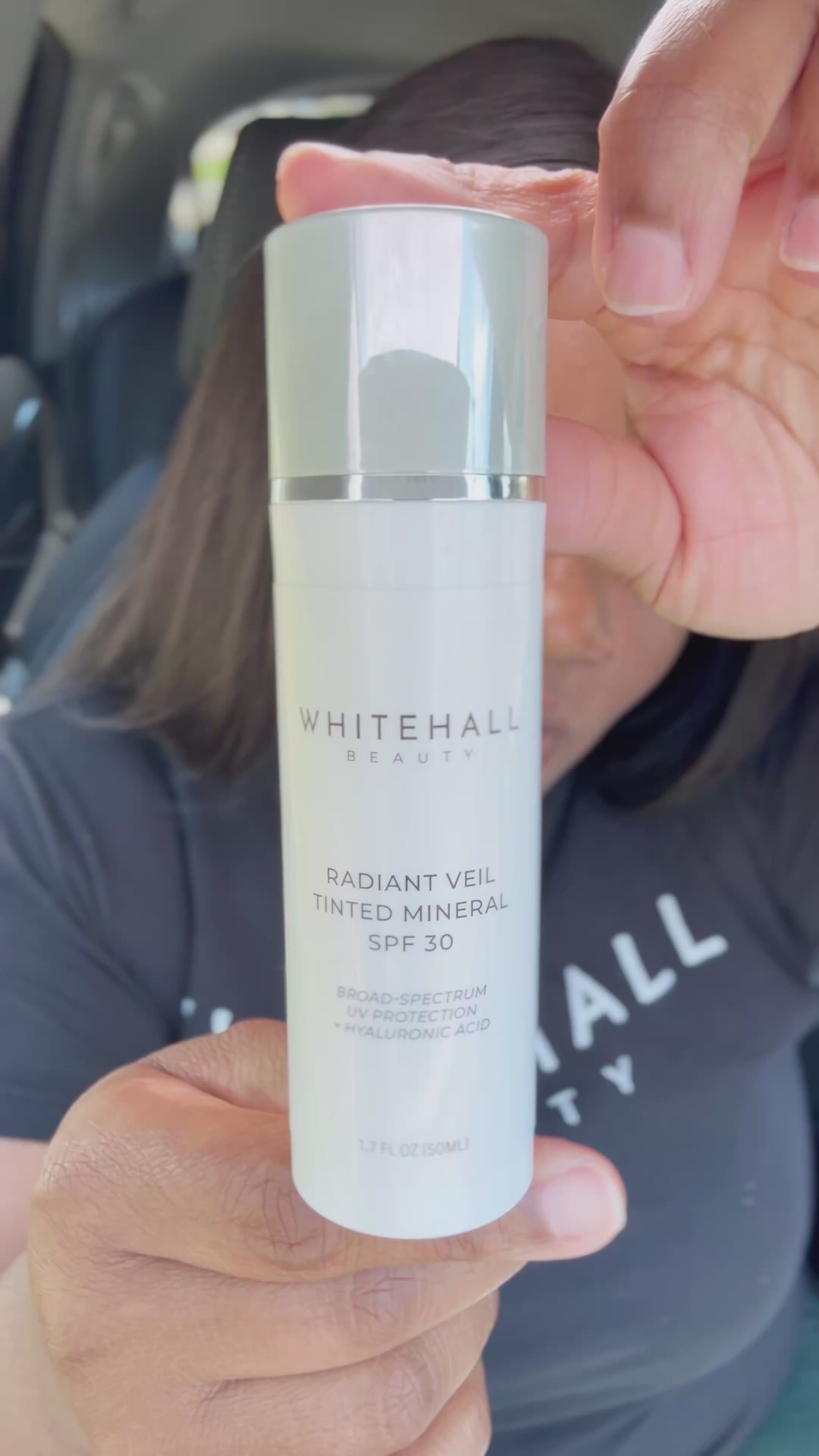 Woman applying Radiant Veil SPF 30 mineral sunscreen outside